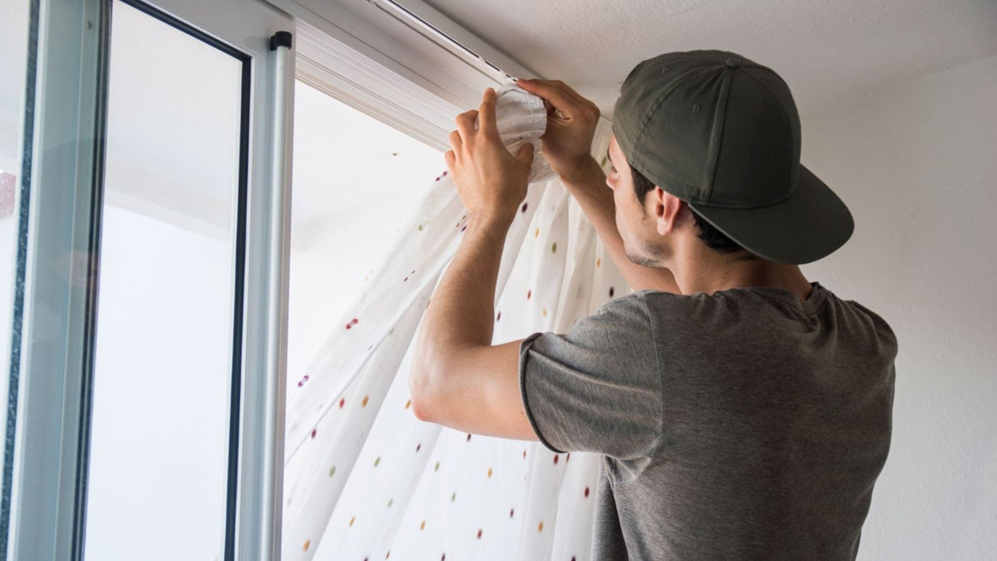 A man carefully measure curtains on a window