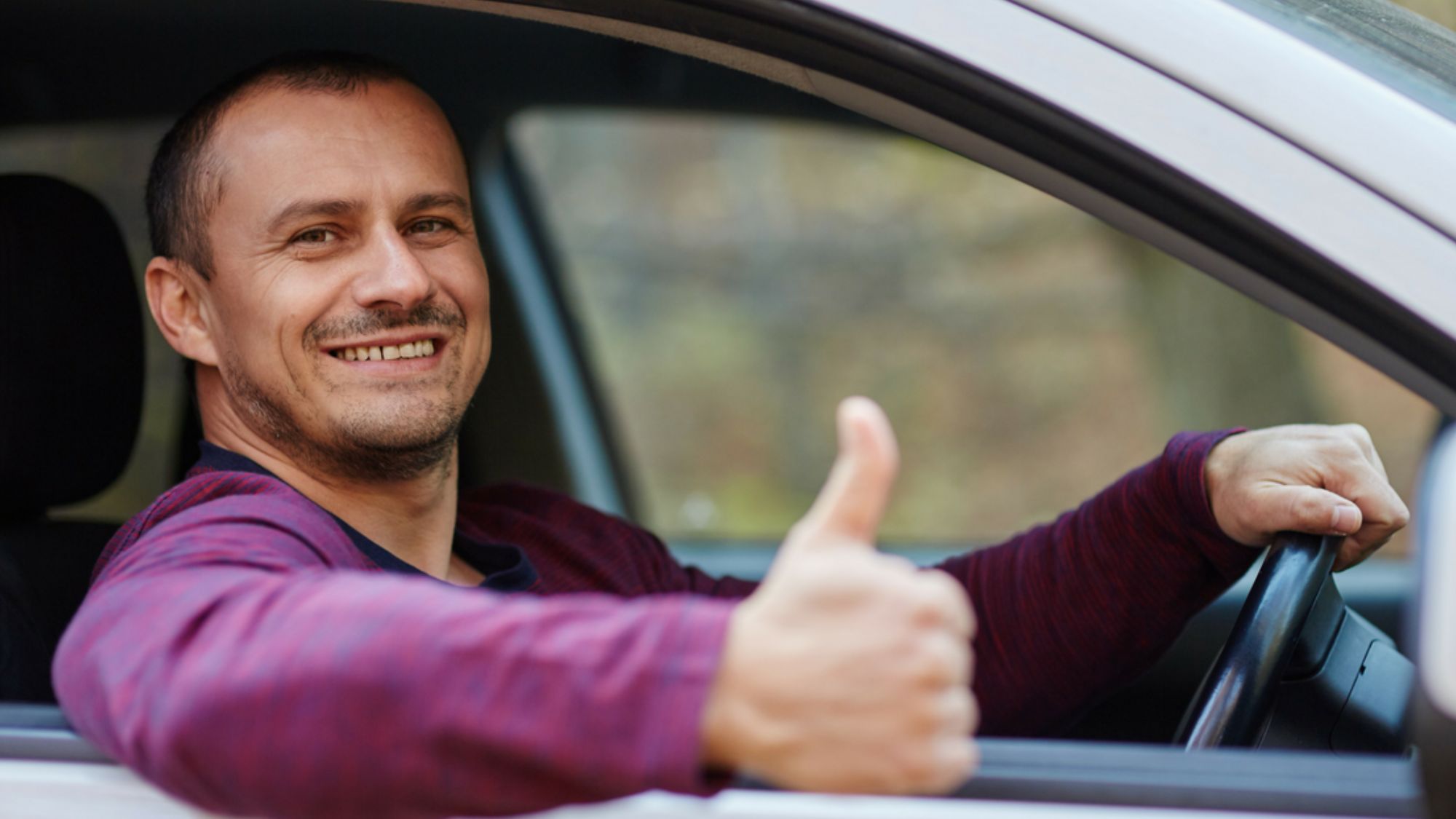 A man in his car giving a thumbs up, demonstrating fitness standards for UK drivers